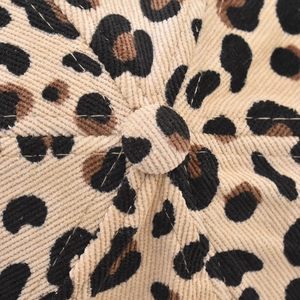 Detailed macro view of the leopard print corduroy texture and top button on a baseball cap