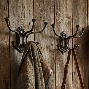 Vintage cast iron antler-style wall hooks with ornate base on rustic wooden wall