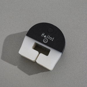 Detail of a U-shaped hair clip with black and frosted matte finish and Hello smiley print