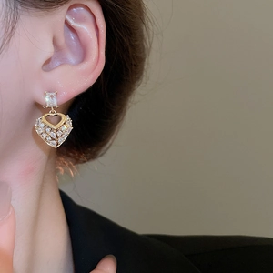 Detail view of heart-shaped drop earrings with gold base and sparkling zircon stones