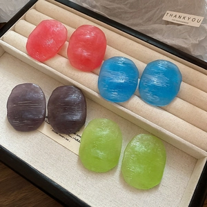 Detailed view of four pairs of oval textured resin earrings in pink, blue, purple, and green