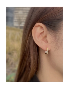 Close-up of gold oval earrings with pearl and cubic zirconia on a model's ear