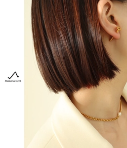 Detail of stainless steel screw earrings and gold necklace with pearl on model