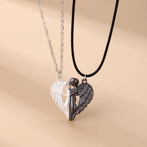 Detail of magnetic angel wing heart pendants in silver and black on a warm background