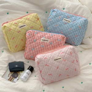 Detail view of quilted plaid makeup bags with bow patterns in soft pastel colors