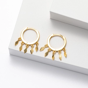 Close-up of golden hoop earrings with five delicate rhombus-shaped metal fringe charms
