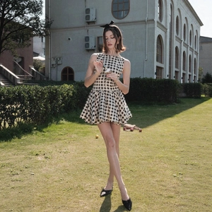 Sleeveless black and white plaid A-line mini dress for women in an elegant outdoor setting