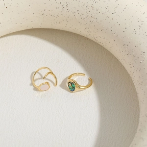 Luxury gold rings featuring abalone shell and pink zircon stones on a white background