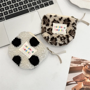 Detail of plush leopard print and polka dot pouches with zippers on a desk
