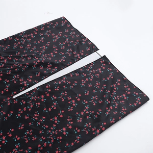 Dettaglio della stampa floreale rossa e dello spacco laterale sul vestito nero