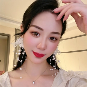 Détail de boucles d'oreilles pendantes en perles blanches avec dentelle sur mannequin