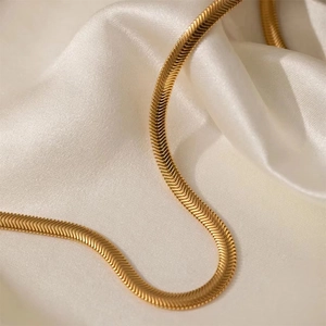 Vue macro d'un collier chaîne serpent doré sur un fond en soie blanche douce