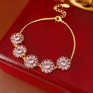 Detail view of gold flower bracelet with purple marquise zirconia on a wood background