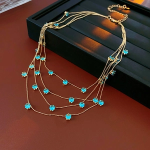 Détail du collier doré multicouche avec pierres de zircon bleues et chaîne d'extension