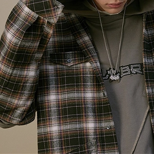 Close-up of retro game controller pendant necklace paired with a plaid flannel shirt