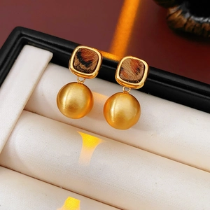 Macro detail of French vintage leopard print earrings with gold brushed spheres in a gift box