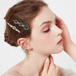 Detailed shot of emerald crystals and pearl hair clips set on a fashion model side profile
