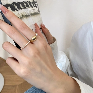 Detail of gold-plated croissant ring and pearl eternity band worn on fingers