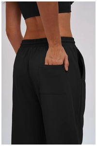 Detail shot of the back elastic waistband and patch pocket on black athletic sweatpants
