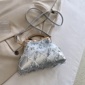 Detail of silver evening clutch bag with sequins, fringe lace and wooden handle