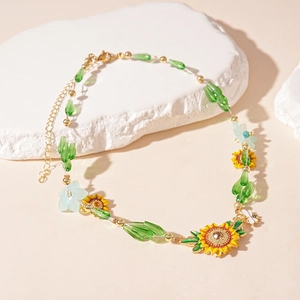 Macro detail of sunflower pendant with green beads and golden chain on stone