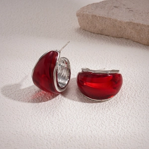 Detailed macro view of red resin C-shape earrings with silver-tone metal edges on stone