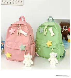 Close-up of macaron pink and green backpacks with cute plush bear and star pendants