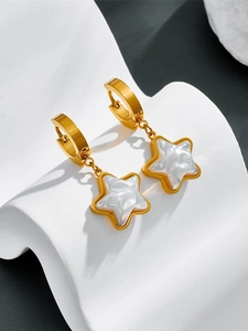 Close-up of gold-plated star pendant earrings with white pearlescent inlay on a wave stand