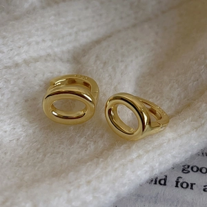 Macro detail of gold-plated S925 sterling silver oval hoop earrings on knit fabric