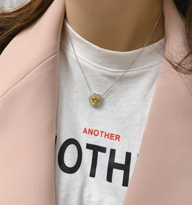 Close-up of yellow heart-shaped diamond pendant on silver chain worn by a model