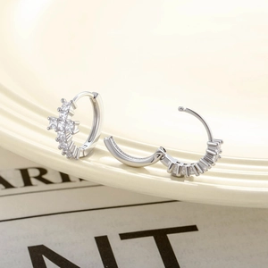 Silver geometric hoop earrings with sparkling zircon and cross charm on a tray