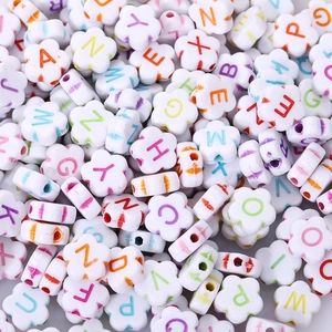 Close-up of white flower-shaped acrylic beads with colorful A-Z alphabet letters for DIY