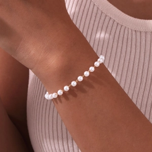 Close-up of gold-plated bracelet with small white pearls on a female wrist detail