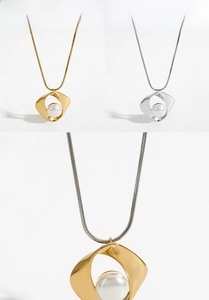 Detail view of gold and silver snake chain necklace with faux pearl geometric pendant