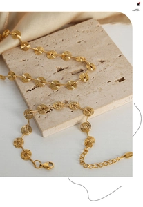 Detail of gold spiral metal bracelet and necklace with lobster clasp on satin
