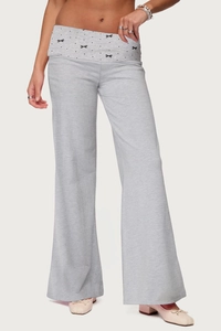 Detail of grey wide-leg trousers featuring a unique fold-over waist with black bow patterns