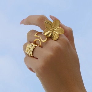 Exaggerated golden irregular flower ring with hammered band on model against blue sky