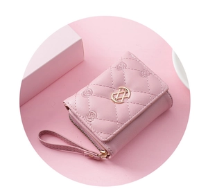Close-up of pink quilted short wallet with gold buckle and embroidery stitch detail