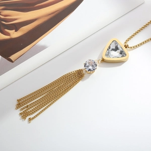 Detailed view of gold tassel necklace with triangular and round zircon stones on a desk
