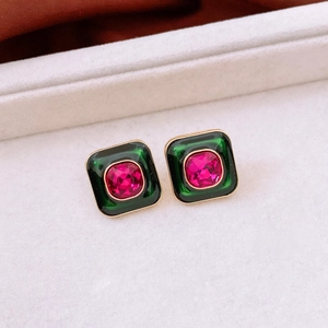Dettaglio di orecchini vintage quadrati con smalto verde e cristallo magenta centrale