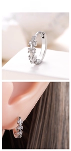 Close-up of silver hoop earrings with star-shaped zircon inlays on model and display stand
