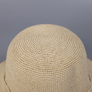 Close-up detail of the spiral woven straw texture on the top of this beige sun hat
