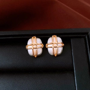 Detail of gold-plated square earrings with white matte texture in a black jewelry box