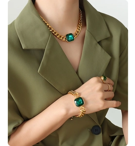 Detail of gold-plated jewelry set with square green crystals on a model