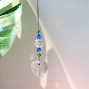 Macro shot of faceted crystal heart suncatcher with rainbow prism effect on green background