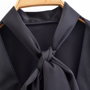 Chic black blouse featuring a lace-up neckline detail on a wooden hanger with soft texture