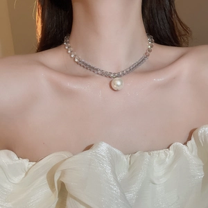 Close-up of elegant beaded choker necklace with a large round pearl pendant on model