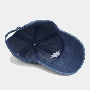 Detail of blue denim baseball cap interior showing sun embroidery and adjustable strap