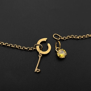 Detailopname van gouden titaniumstalen ketting met hartsleutel en geel kristal