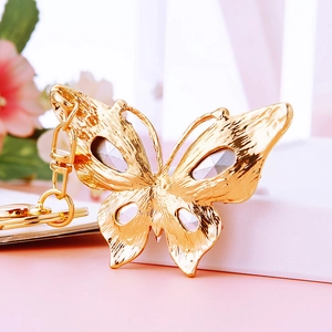 Detail of golden butterfly keychain with grey crystals and hollow wing patterns